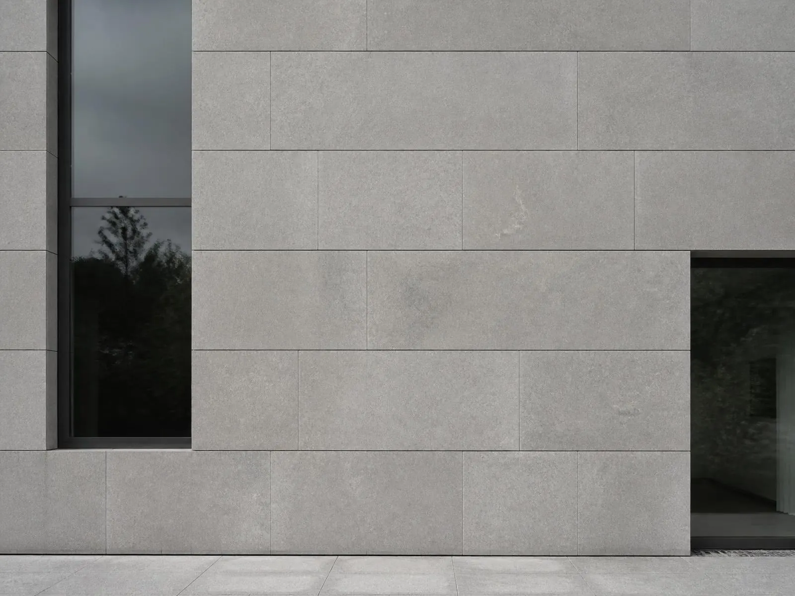 Indicative visualisation of an external elevation clad in large-format cool grey limestone panels in a regular stack bond, with flat open joints