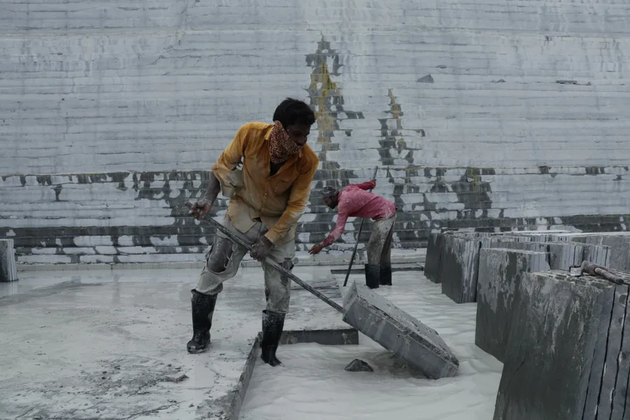 A cut layer of limestone being lifted clear of the bed in one piece